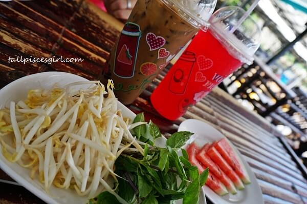 Our drinks, raw bean sprouts, leaves and complimentary watermelons